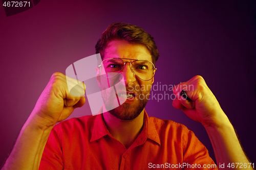 Image of The young emotional angry man screaming on pink studio background