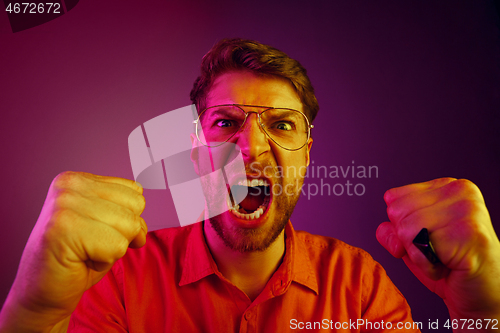 Image of The young emotional angry man screaming on pink studio background