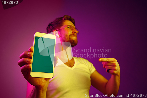 Image of Indoor portrait of attractive young man holding blank smartphone