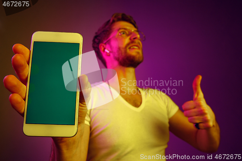 Image of Indoor portrait of attractive young man holding blank smartphone