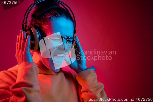 Image of Fashion pretty woman with headphones listening to music over neon background