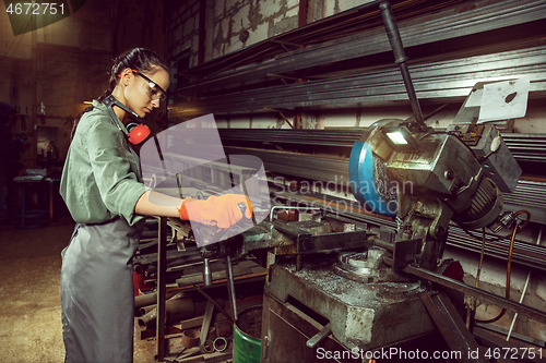 Image of Busy and serious craftswoman grinding timbers with special machine.