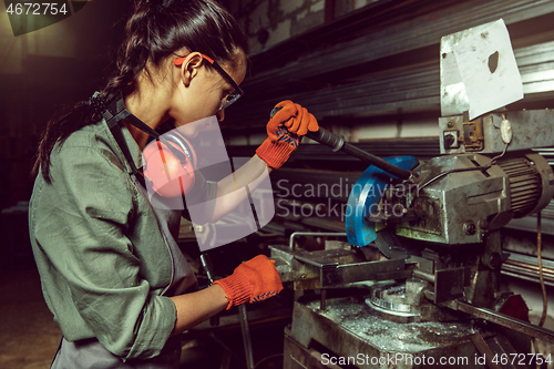 Image of Busy and serious craftswoman grinding timbers with special machine.