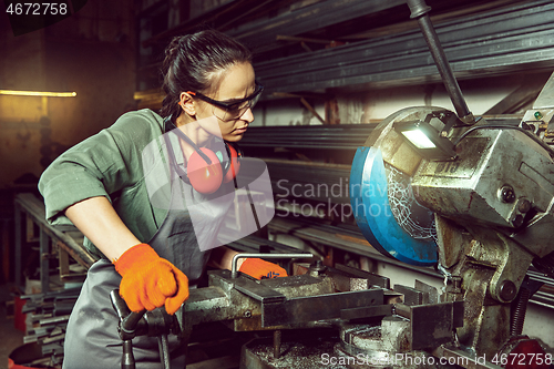 Image of Busy and serious craftswoman grinding timbers with special machine.