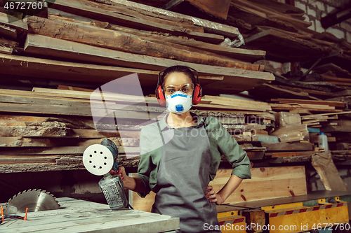 Image of Busy and serious craftswoman grinding timbers with special machine.