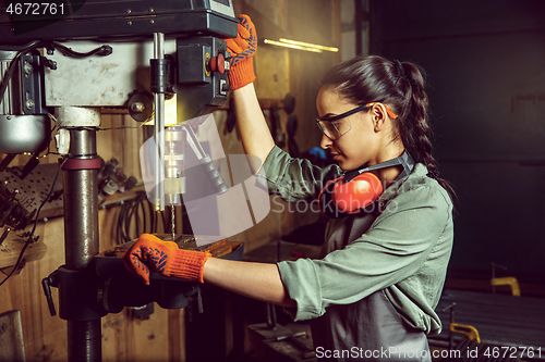 Image of Busy and serious craftswoman grinding timbers with special machine.