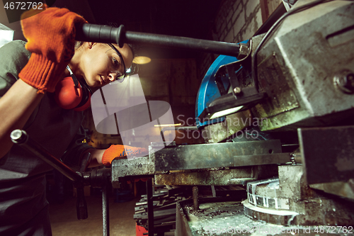 Image of Busy and serious craftswoman grinding timbers with special machine.