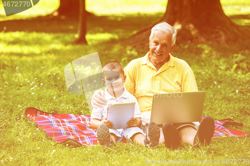 Image of grandfather and child in park using tablet