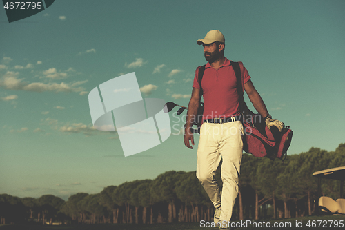 Image of golfer  walking and carrying golf  bag