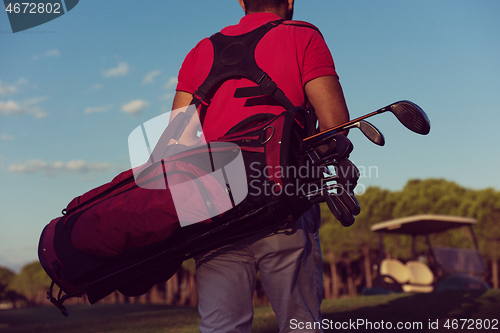 Image of close up of golfers back while   walking and carrying golf  bag