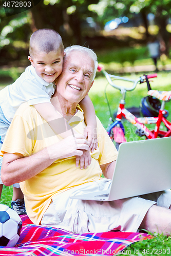 Image of grandfather and child using laptop