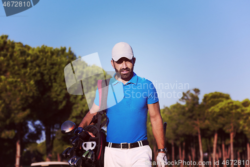 Image of golfer  walking and carrying golf  bag