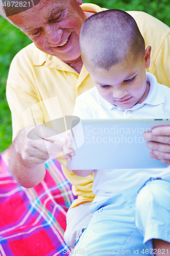 Image of grandfather and child in park using tablet