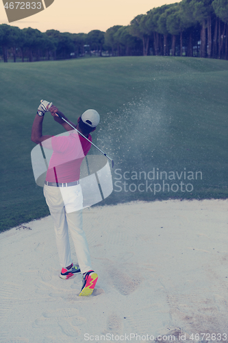 Image of golfer hitting a sand bunker shot on sunset