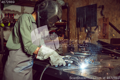 Image of Busy and serious craftswoman grinding timbers with special machine.