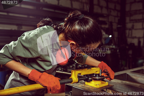 Image of Busy and serious craftswoman grinding timbers with special machine.