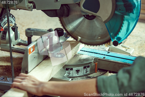 Image of Busy and serious craftswoman grinding timbers with special machine.