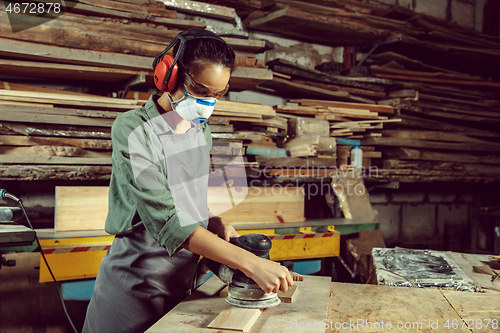 Image of Busy and serious craftswoman grinding timbers with special machine.