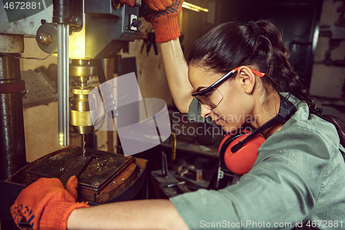 Image of Busy and serious craftswoman grinding timbers with special machine.