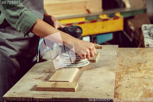 Image of Hands of craftswoman grinding timbers with special machine.