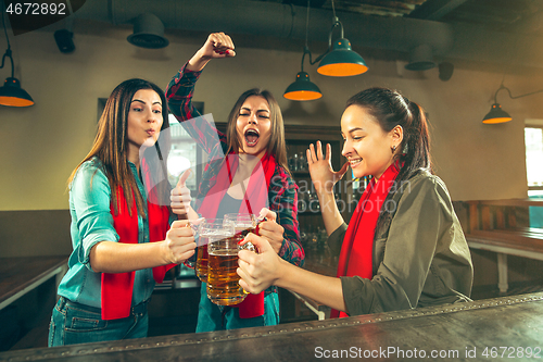 Image of Sport, people, leisure, friendship and entertainment concept - happy football fans or female friends drinking beer and celebrating victory at bar or pub