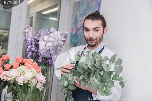 Image of Small business. Male florist in flower shop. Floral design studio, making decorations and arrangements.