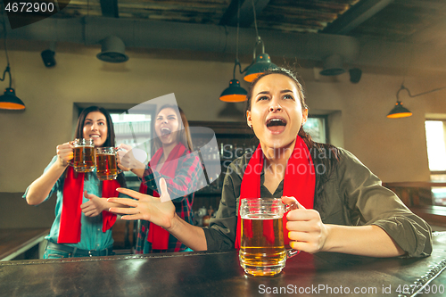 Image of Sport, people, leisure, friendship and entertainment concept - happy football fans or female friends drinking beer and celebrating victory at bar or pub
