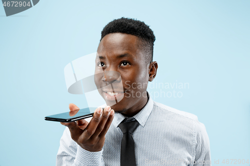 Image of Indoor portrait of attractive young black man holding blank smartphone