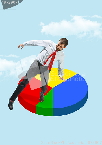 Image of Businessman balancing on a pie chart