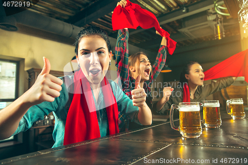 Image of Sport, people, leisure, friendship and entertainment concept - happy football fans or female friends drinking beer and celebrating victory at bar or pub