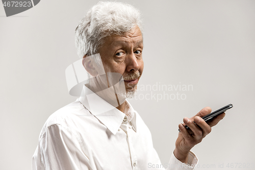 Image of Indoor portrait of senior man holding blank smartphone