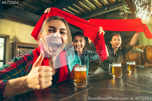 Image of Sport, people, leisure, friendship and entertainment concept - happy football fans or female friends drinking beer and celebrating victory at bar or pub