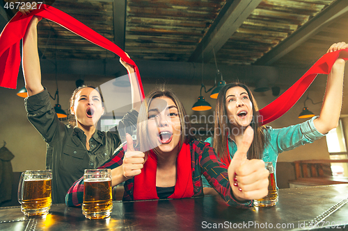 Image of Sport, people, leisure, friendship and entertainment concept - happy football fans or female friends drinking beer and celebrating victory at bar or pub