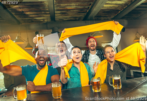 Image of Sport, people, leisure, friendship and entertainment concept - happy football fans or male friends drinking beer and celebrating victory at bar or pub