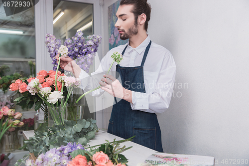 Image of Small business. Male florist in flower shop. Floral design studio, making decorations and arrangements.