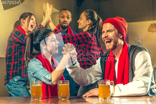 Image of Sport, people, leisure, friendship and entertainment concept - happy football fans or male friends drinking beer and celebrating victory at bar or pub