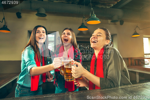 Image of Sport, people, leisure, friendship and entertainment concept - happy football fans or female friends drinking beer and celebrating victory at bar or pub