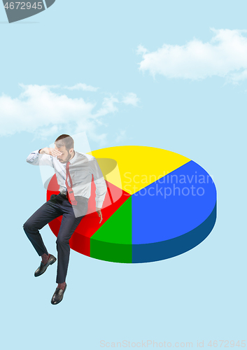 Image of Businessman sitting on a pie chart