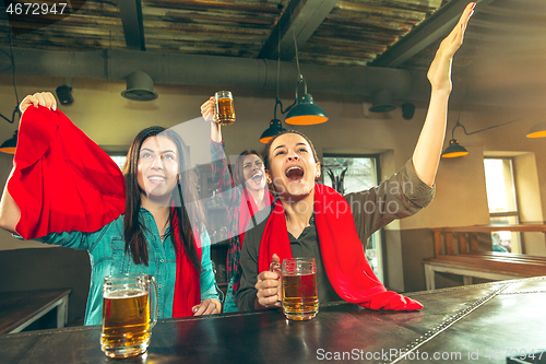 Image of Sport, people, leisure, friendship and entertainment concept - happy football fans or female friends drinking beer and celebrating victory at bar or pub