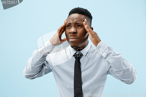 Image of Man having headache. Isolated over blue background.