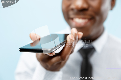 Image of Indoor portrait of attractive young black man holding blank smartphone