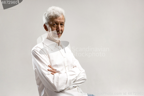 Image of The serious businessman standing and looking at camera against gray background.