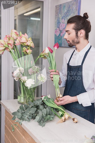 Image of Small business. Male florist in flower shop. Floral design studio, making decorations and arrangements.