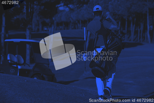 Image of golfer  walking and carrying golf  bag