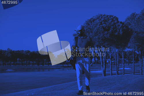 Image of golfer  walking and carrying bag