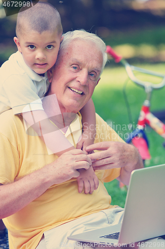 Image of grandfather and child using laptop