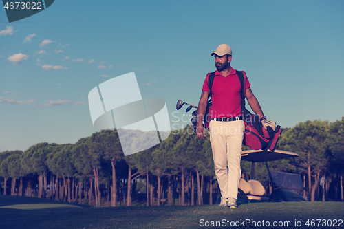 Image of golfer  walking and carrying golf  bag