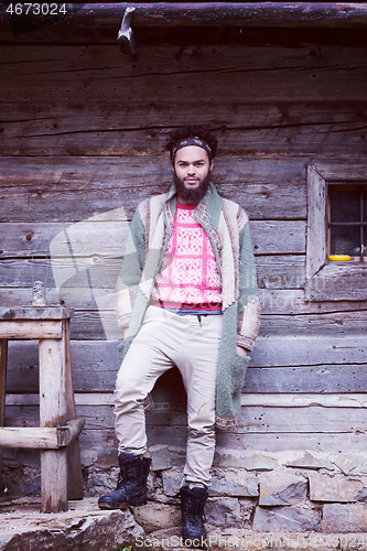 Image of portrait of young hipster in front of wooden house