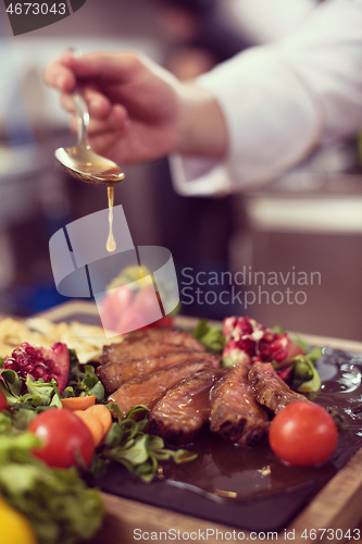 Image of Chef hand finishing steak meat plate