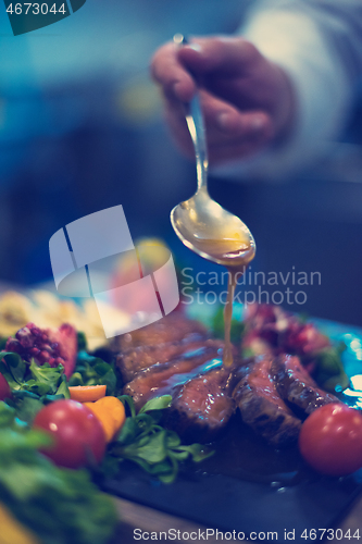 Image of Chef hand finishing steak meat plate